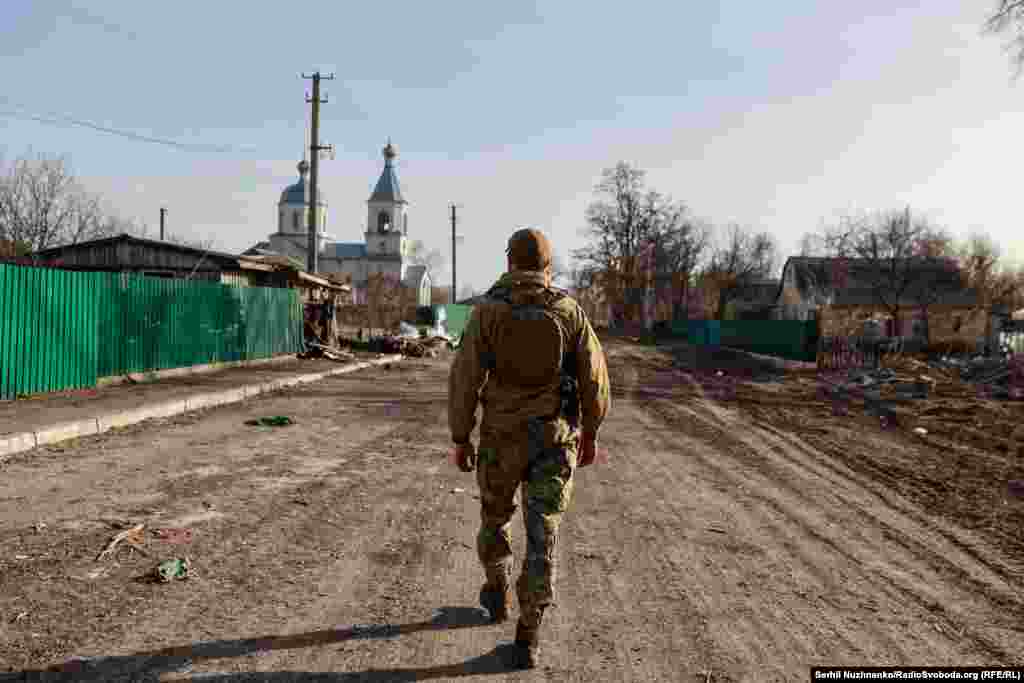 На первом изображении: украинский военный, сражавшийся за освобождение Лукьяновки и соседнего села Рудницкого, идёт по улице в марте 2022 года. На втором изображении: улица в Рудницком в марте 2024 года &nbsp;