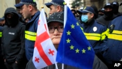 Žena sa zastavama EU i Gruzije stoji ispred policije koja blokira ulicu tokom opozicionog skupa u Tbilisiju. (arhivska fotografija)