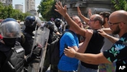 People in Belgrade react as Serbian police remove a street blockade on June 30. 